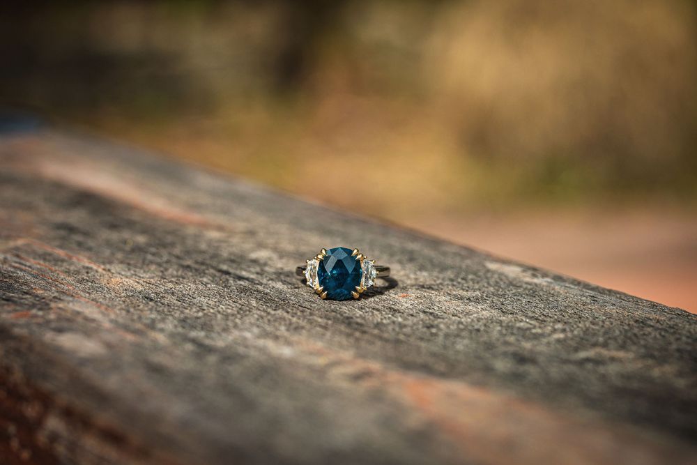 A macro photography sequence showing a blue sapphire ring on textured stone surface in natural lighting.