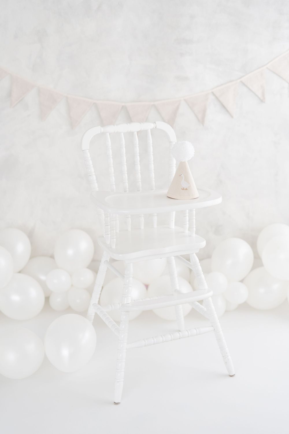 Décor de fête blanc et lumineux pour une séance anniversaire smash the cake en studio