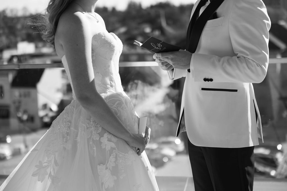 A black and white photo captures steam rising between a couple in wedding attire on their special day.