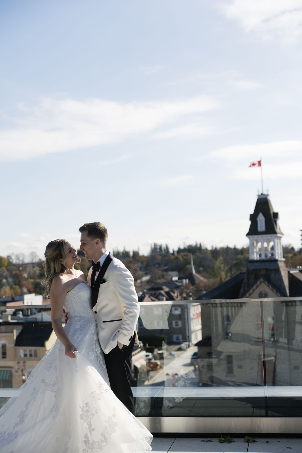 Newlyweds share an intimate moment on a rooftop balcony overlooking an urban landscape.