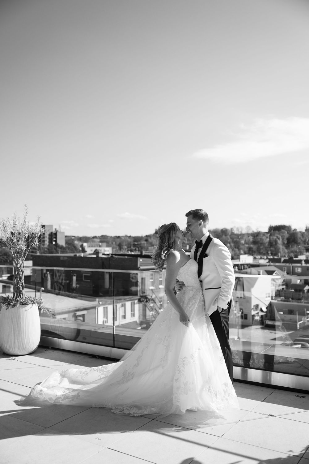 Black and white wedding photography captures a couple's romantic rooftop moments against a cityscape.
