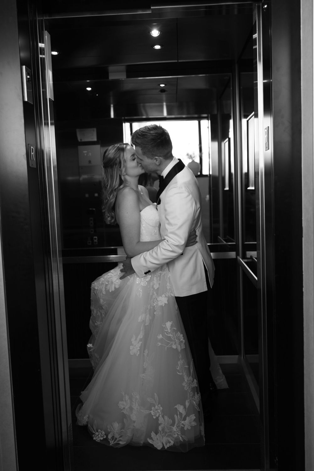 Wedding couple reflected in dark hallway mirrors creating a dramatic composition.