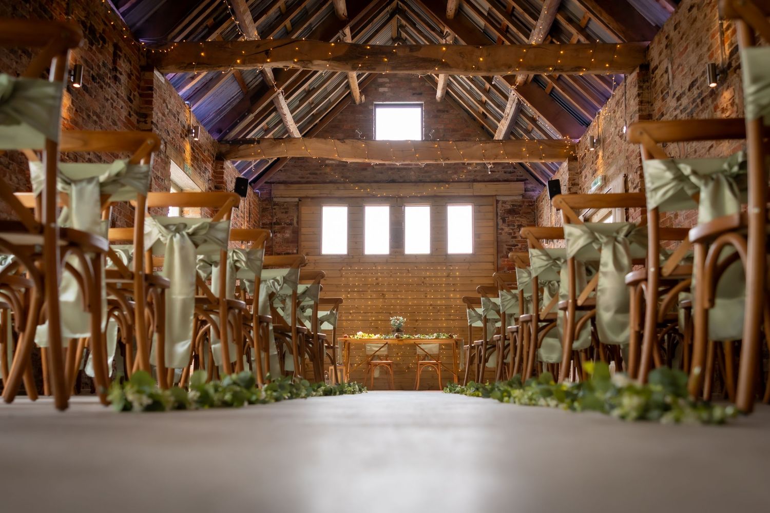 Interior of a rustic wooden barn with exposed beams and natural light streaming through windows. Sedgewell Barn Northallerton Wedding
