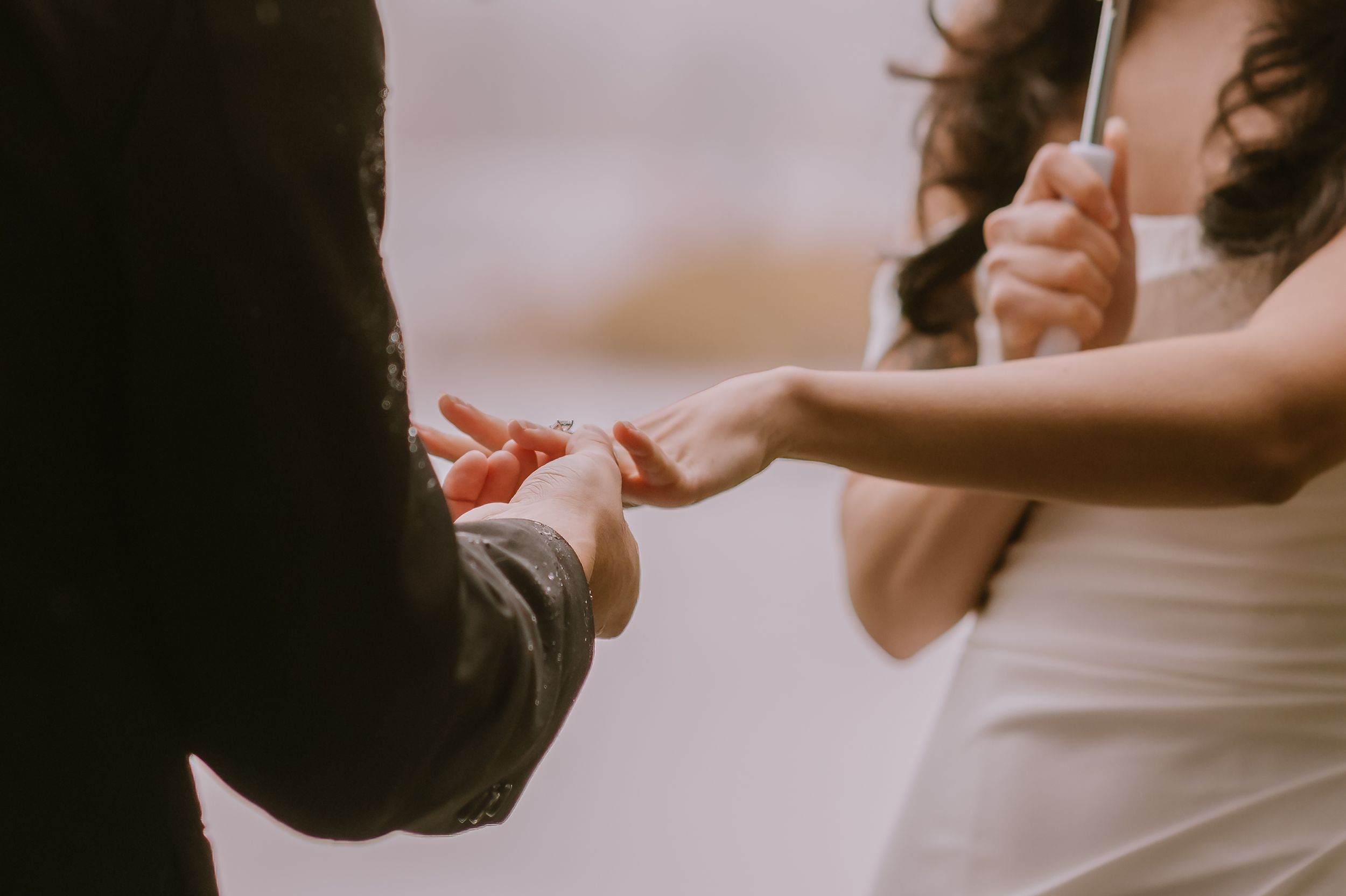 Close-up shot of hands exchanging wedding rings during an intimate ceremony.