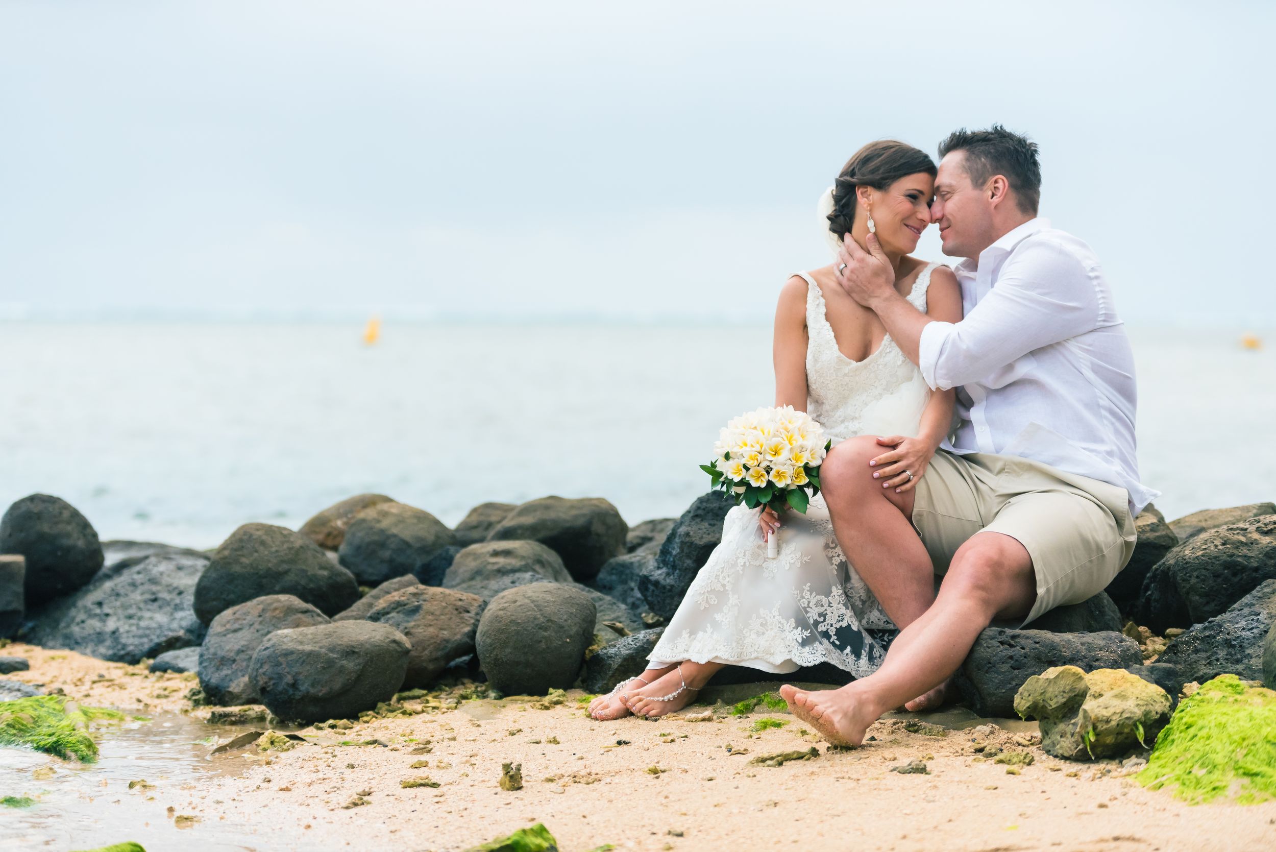Beach photography session with volcanic rocks and ocean backdrop.
