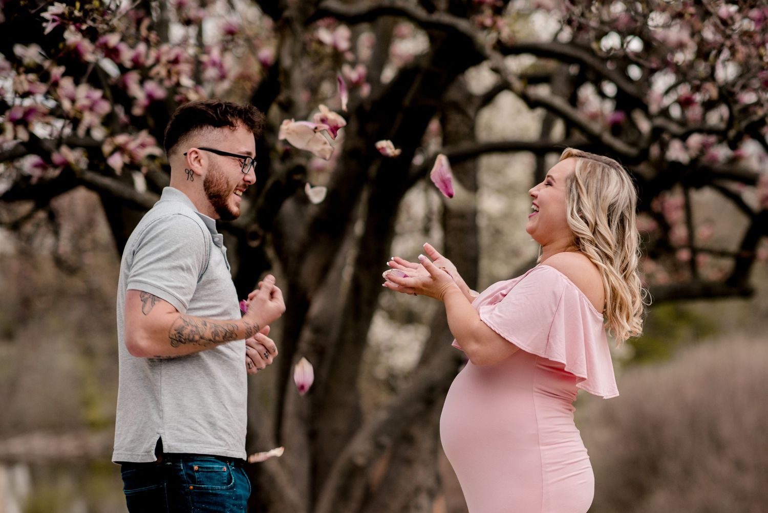 A couple dances together under blooming cherry blossom trees in a romantic spring photoshoot.
