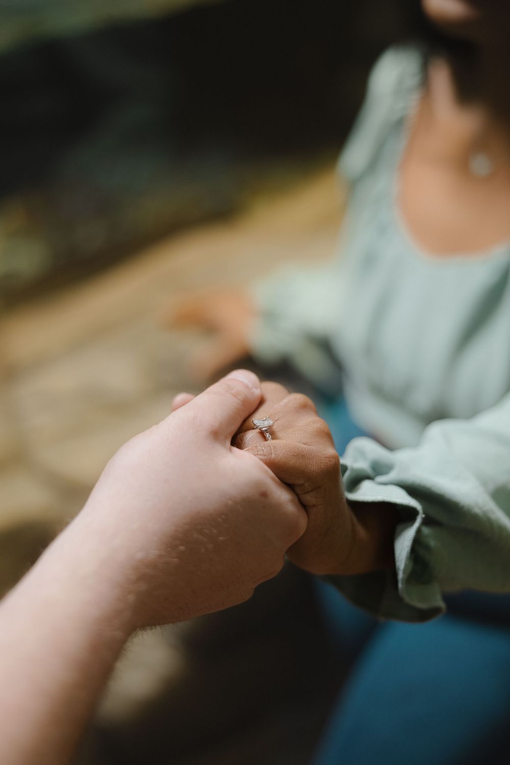 Close-up view of two hands reaching out and holding each other in a caring gesture against a blurred background.