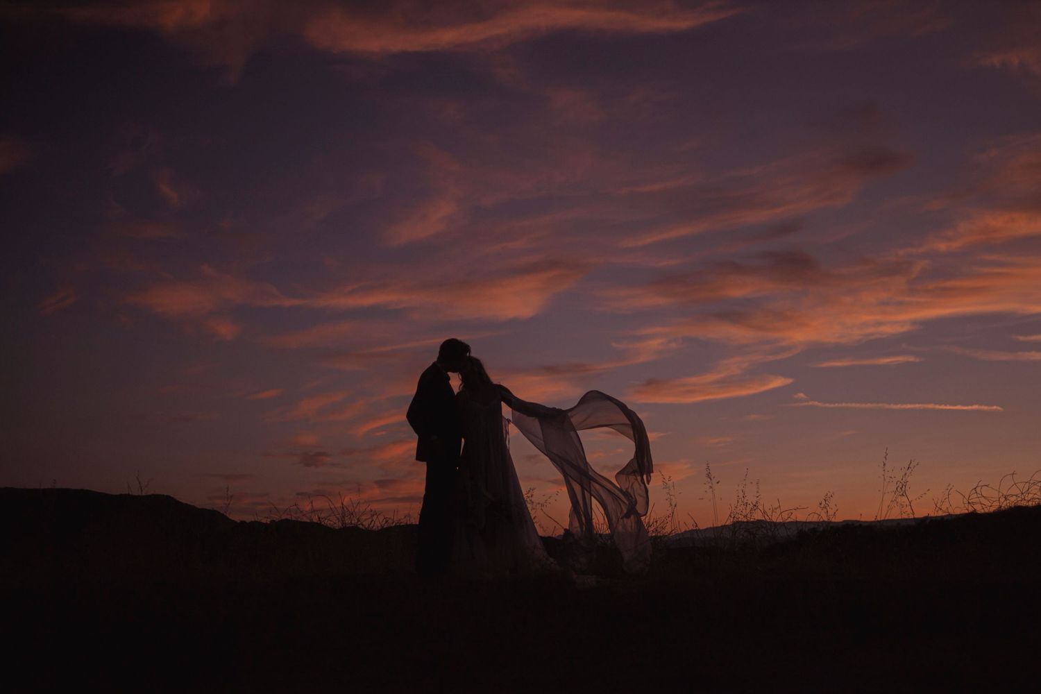 couple kisses among the landscape and gradient sky at their outdoor, mountain intimate wedding quebec canada, during dusk.