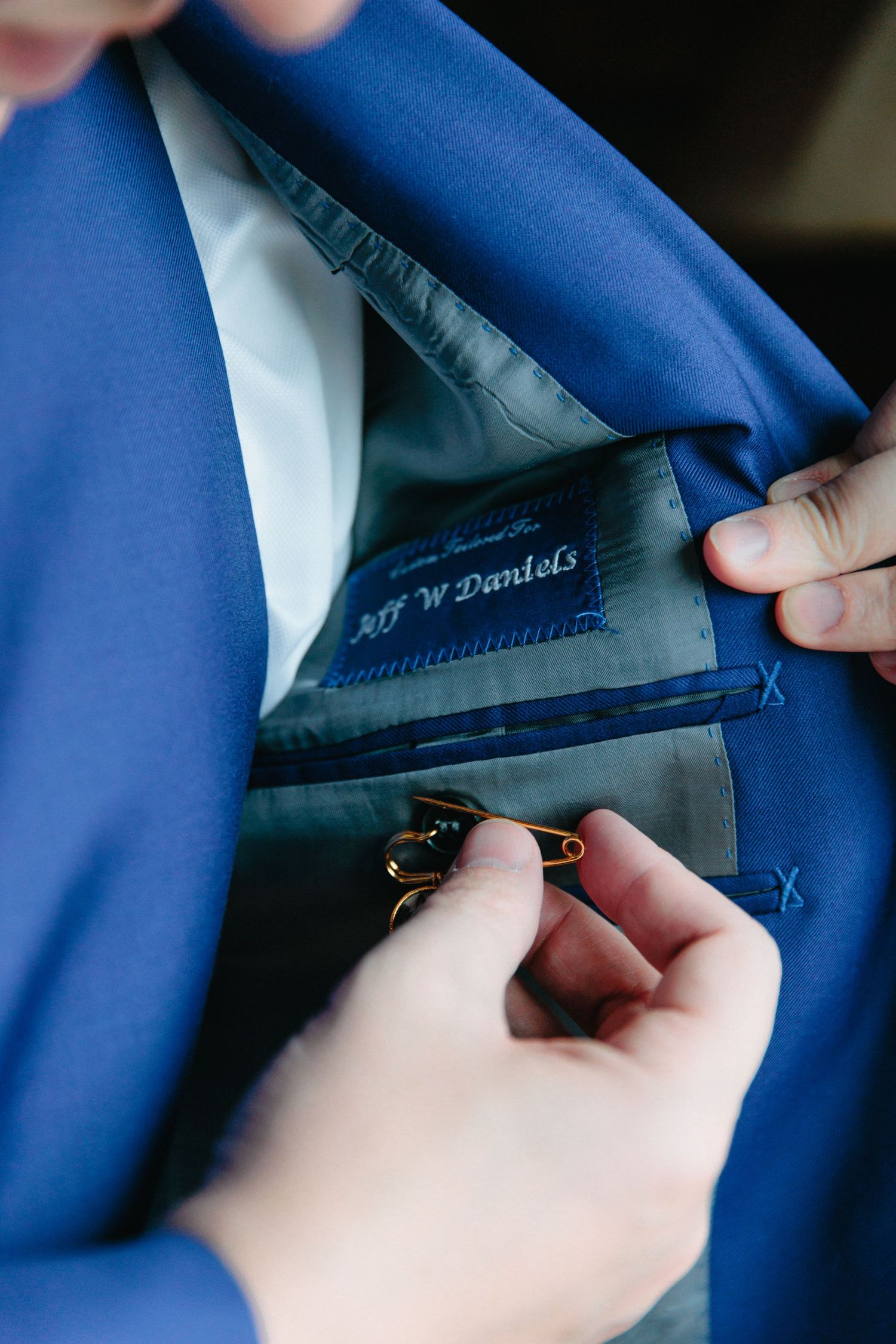 Close-up of blue suit jacket lining being adjusted to show custom tailoring details.