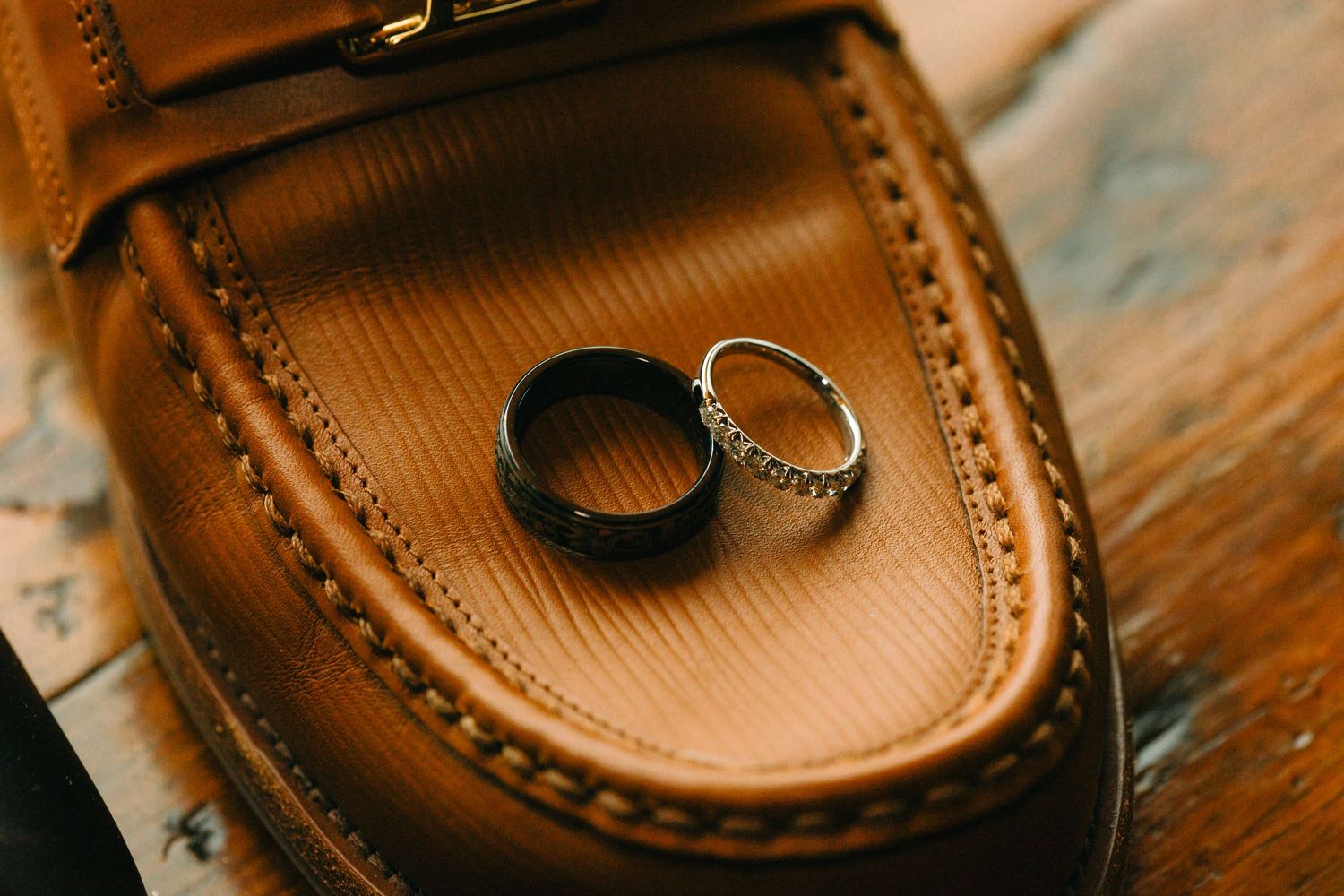 Closeup detail of brown leather boat shoes showing classic moccasin stitching and laces against a wooden surface.