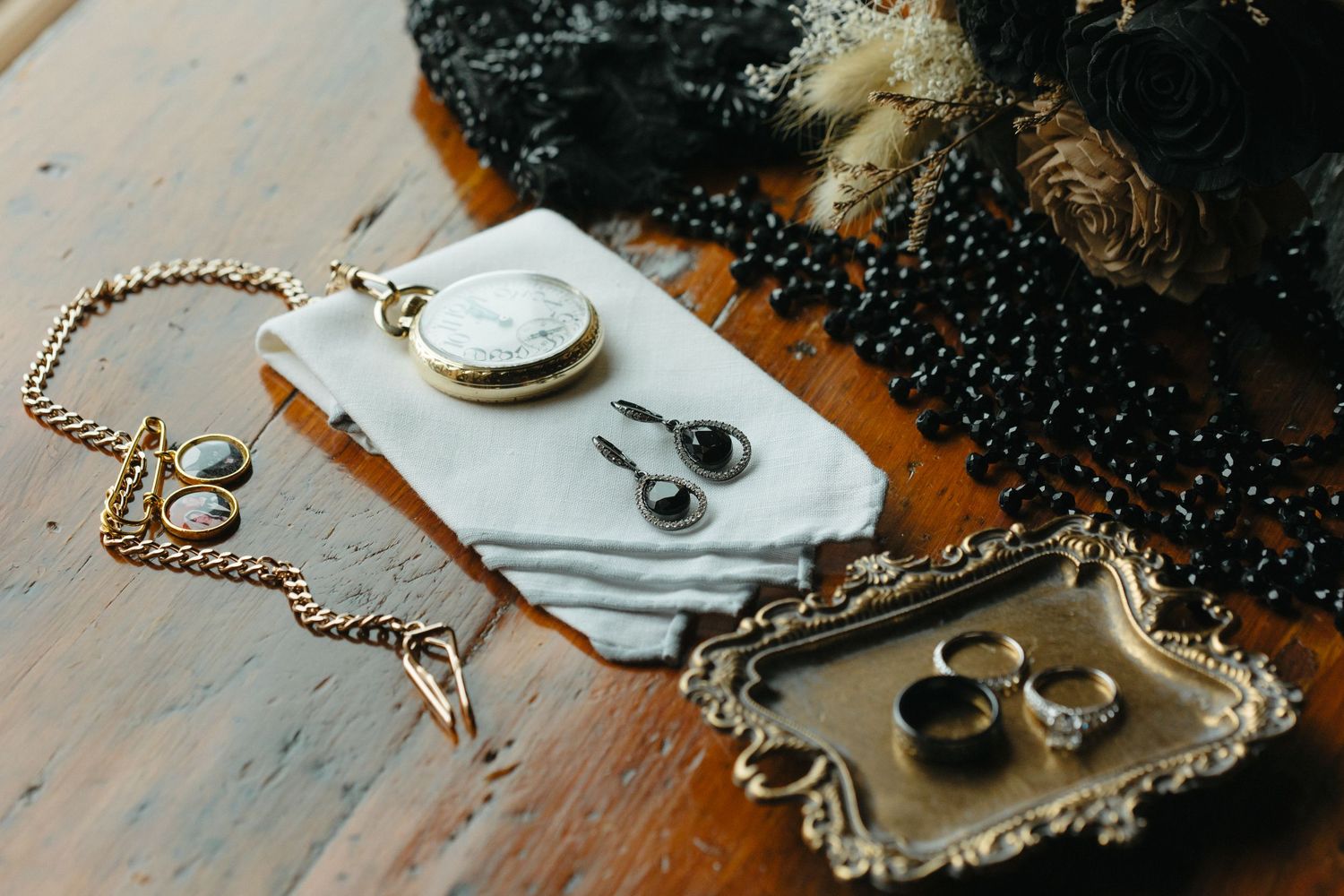 A vintage gold pocket watch with chain lies on a rustic wooden surface next to scattered coffee beans.