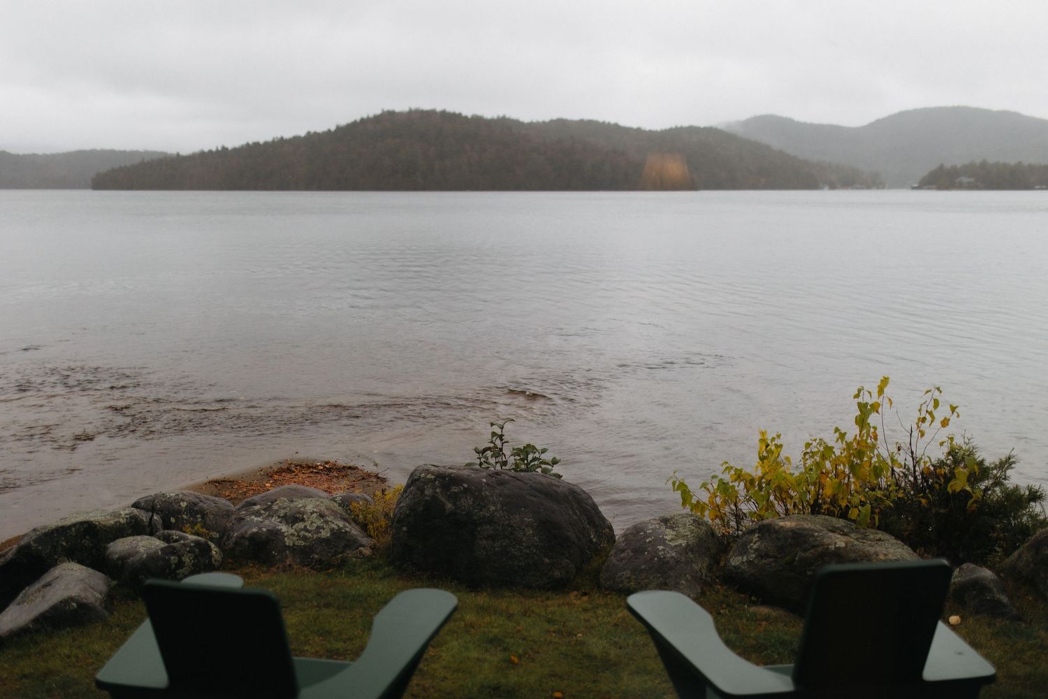 Panoramic view of misty mountains and lake on overcast day.