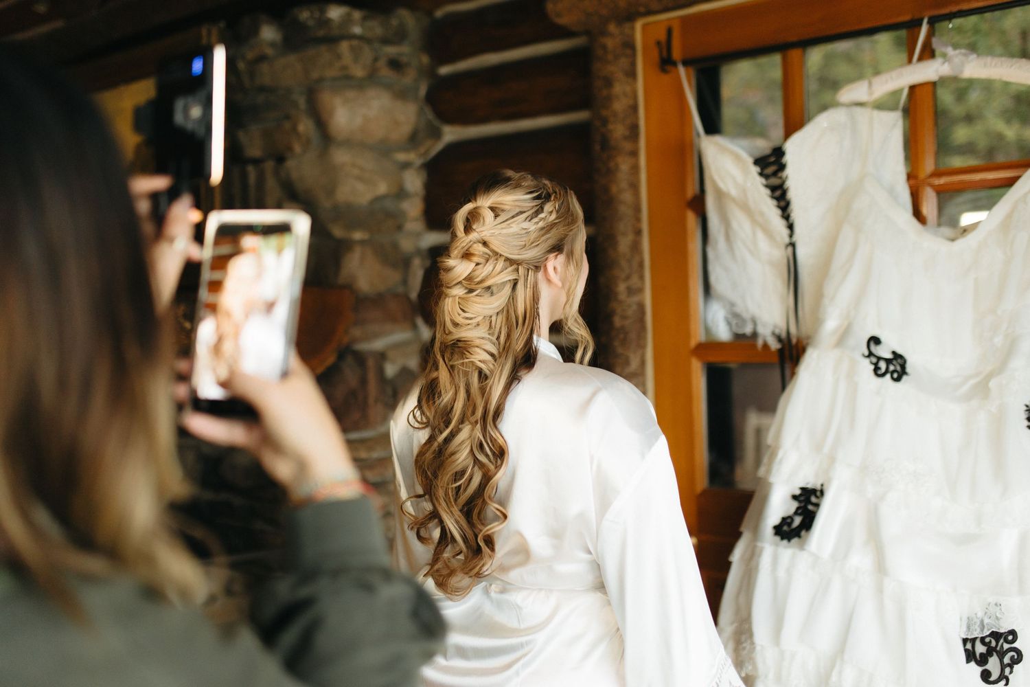 Someone photographs a white wedding dress hanging while getting ready for the ceremony.