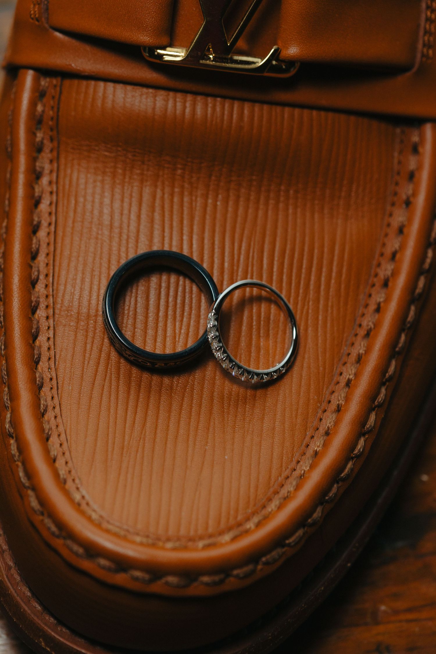 Two wedding rings displayed on brown leather showing intricate details and texture.