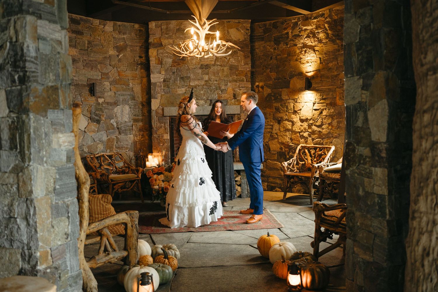 A rustic stone chapel interior with chandeliers and decorative lighting creates an intimate wedding ceremony atmosphere.