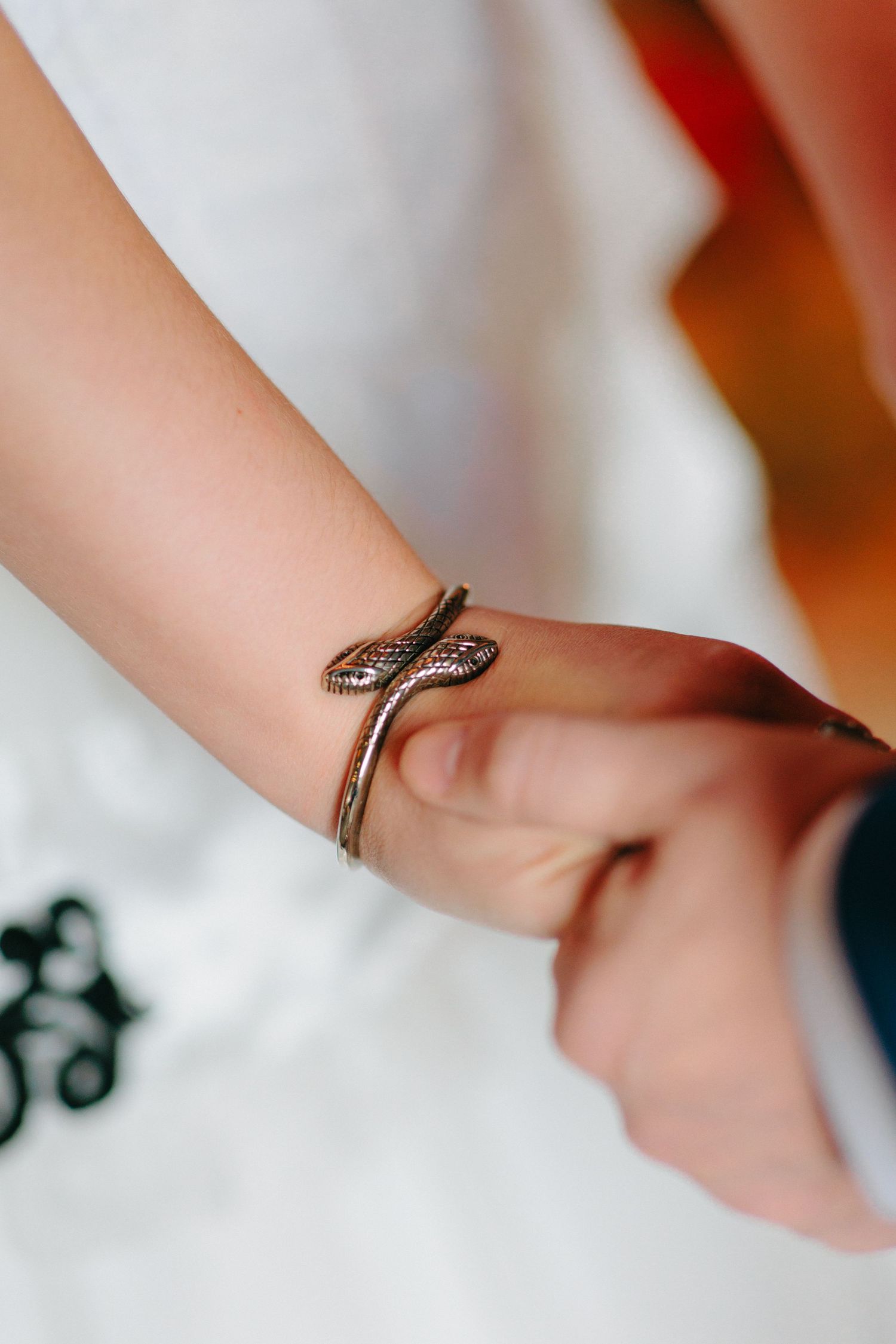 Close-up of a delicate snake-shaped bracelet wrapped around a wrist.