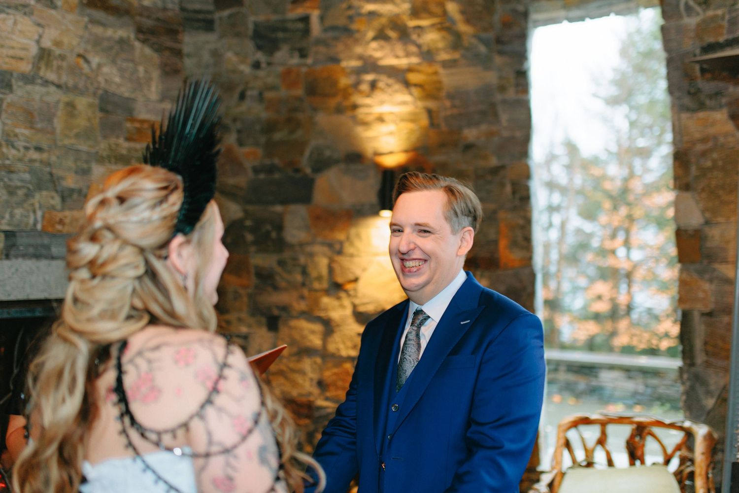 A candid wedding moment captured in a rustic stone venue with natural lighting.