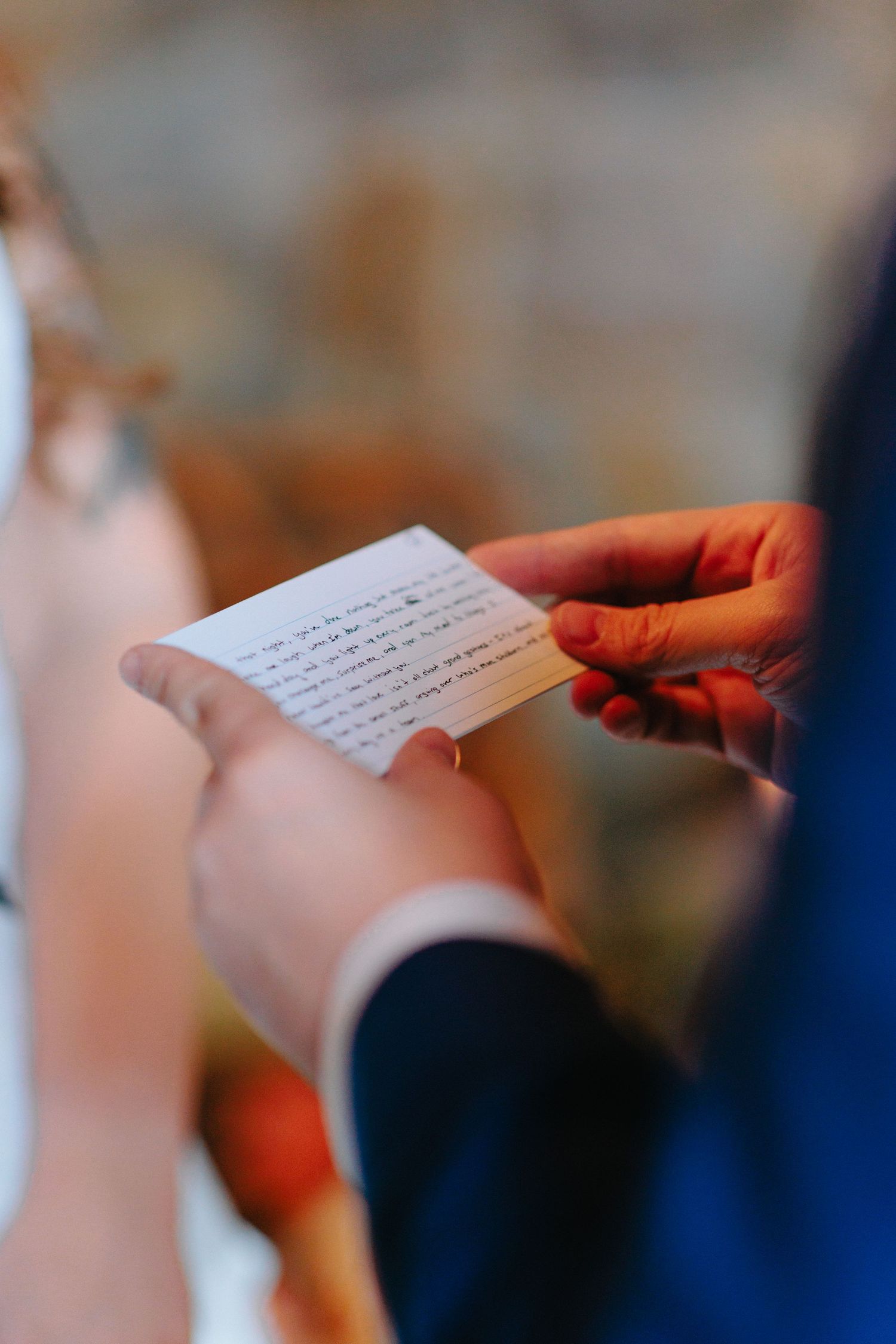 Hands holding and reading a handwritten letter or note against a blurred background.