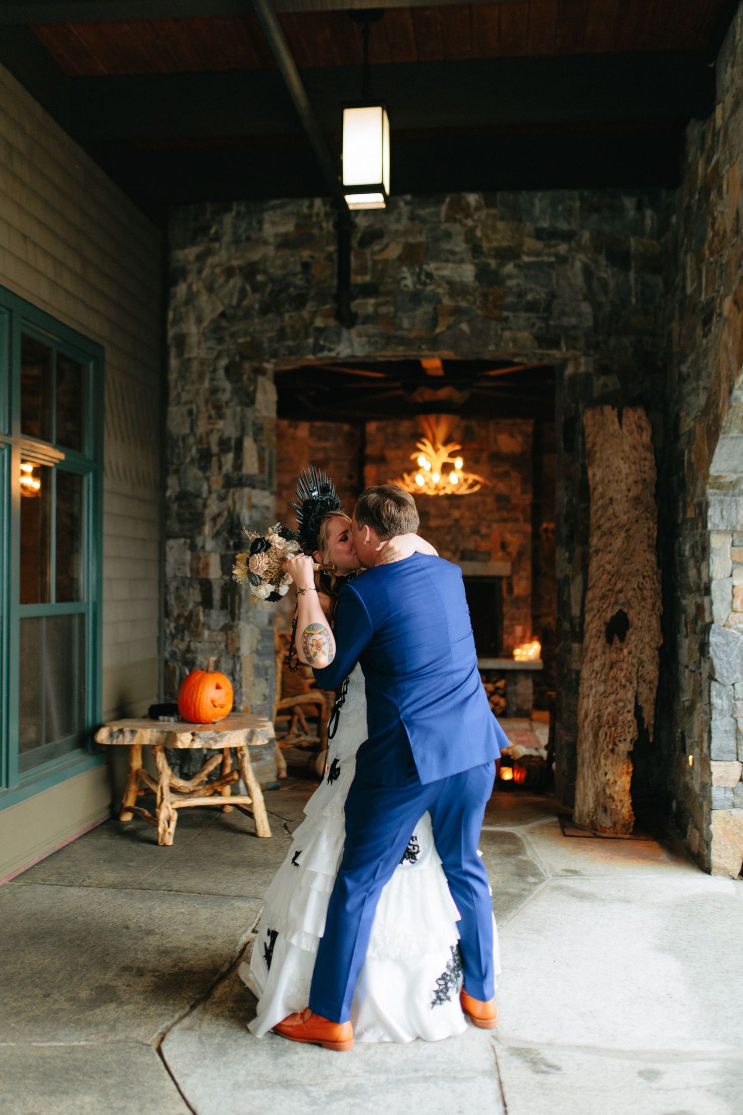 A romantic moment between a couple dancing near a stone fireplace decorated with pumpkins for fall.