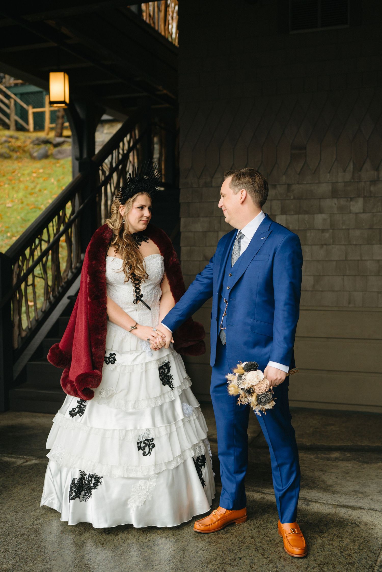 A couple in wedding attire share an intimate moment under dim lighting, with the bride in a white dress with black accents.