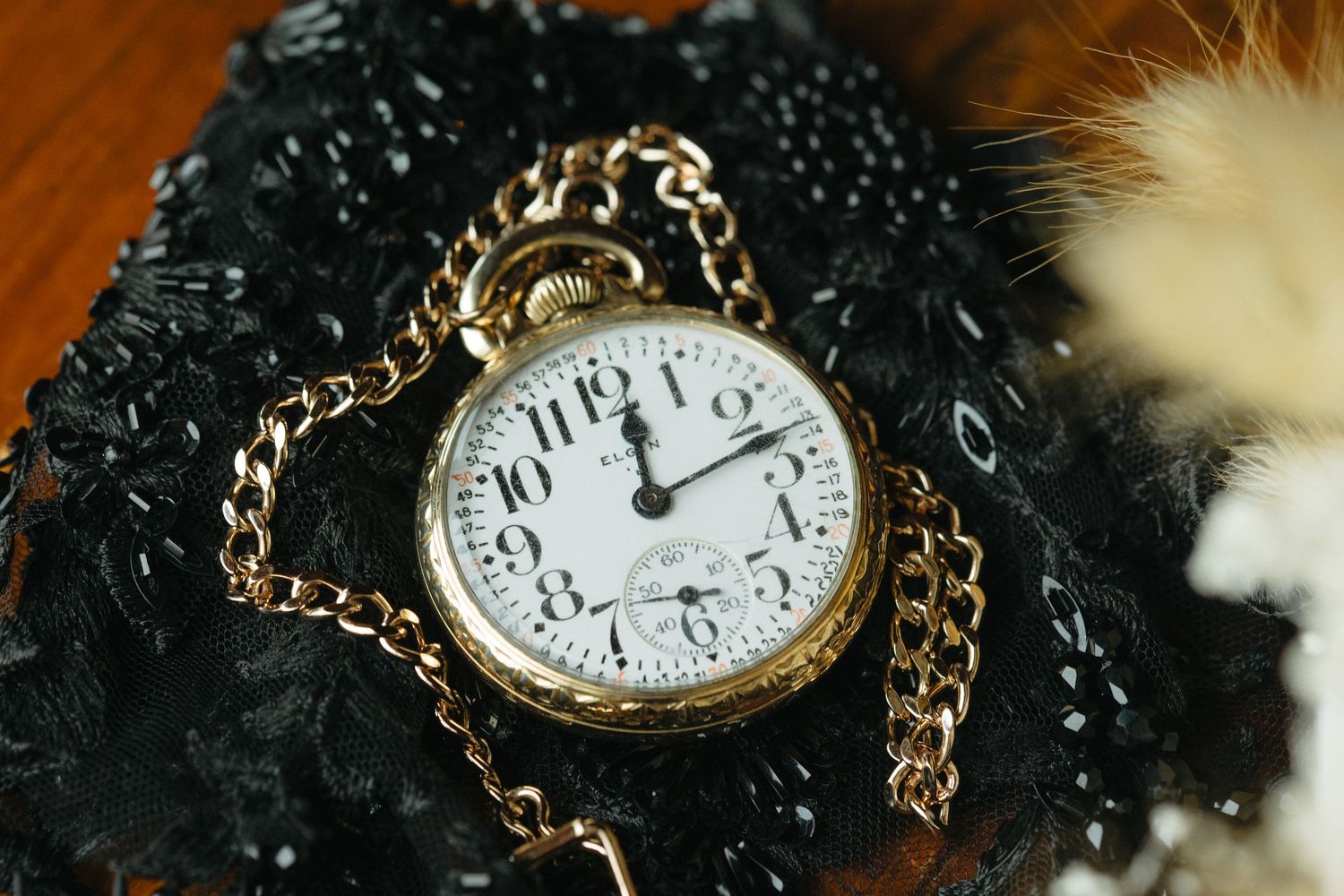 Vintage pocket watch with gold chain lying in dark water droplets creating a dramatic moody atmosphere.
