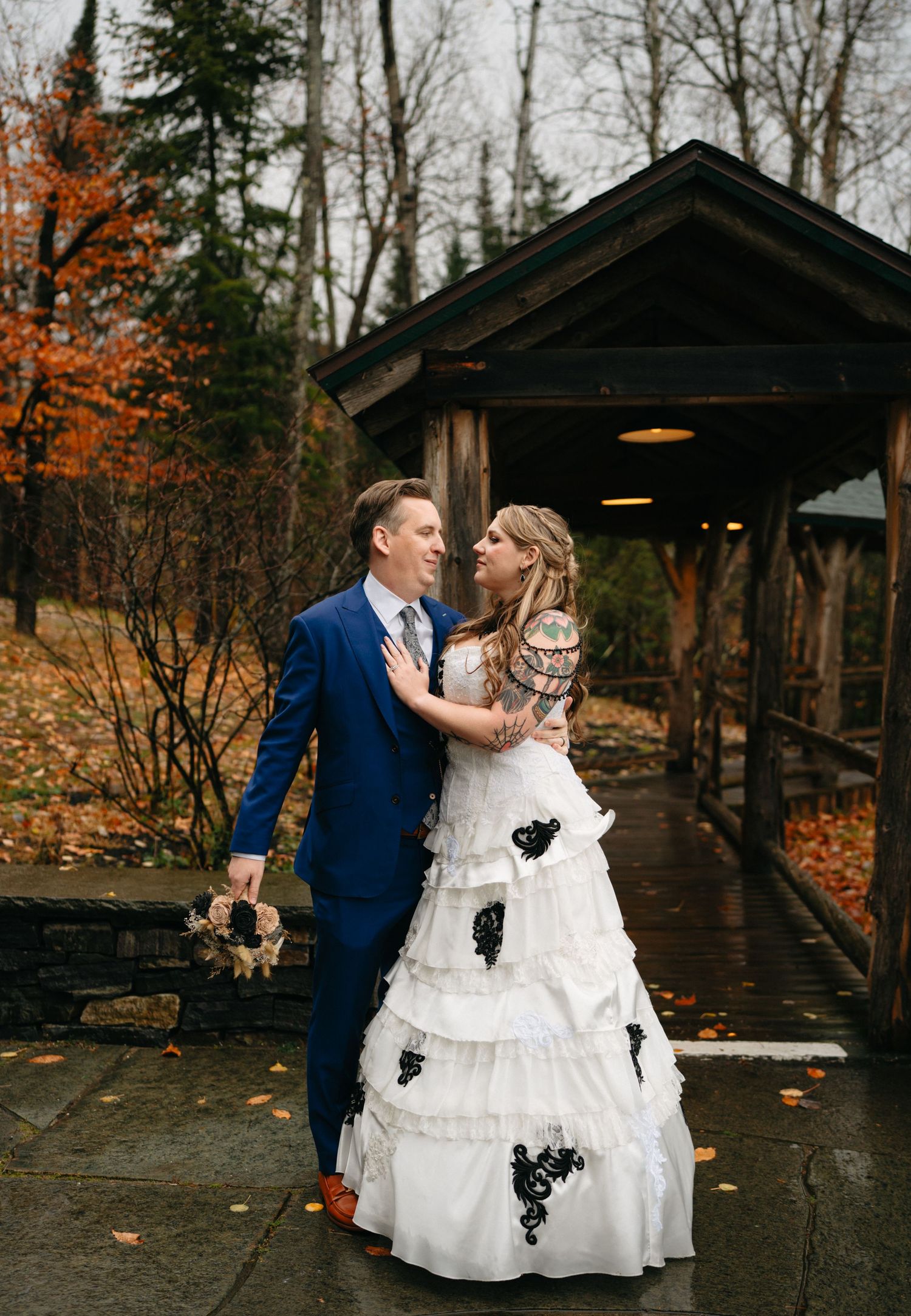 A romantic wedding portrait on a covered bridge with fall colors in the background.