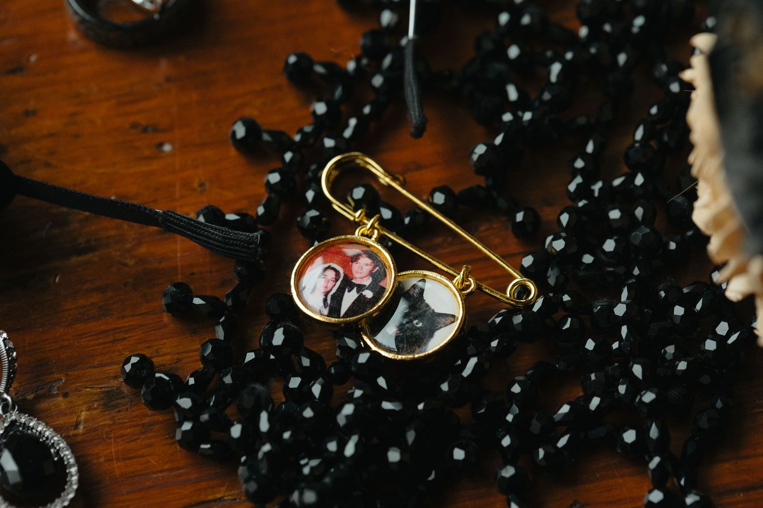 Black pearl beaded necklace arranged artistically on dark wooden surface.