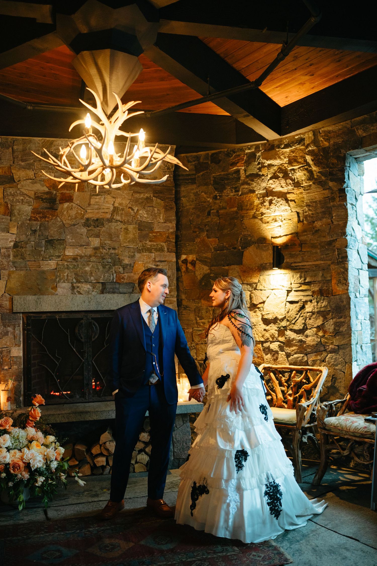 Couple dances together in rustic stone room with antler chandeliers creating warm romantic ambiance.