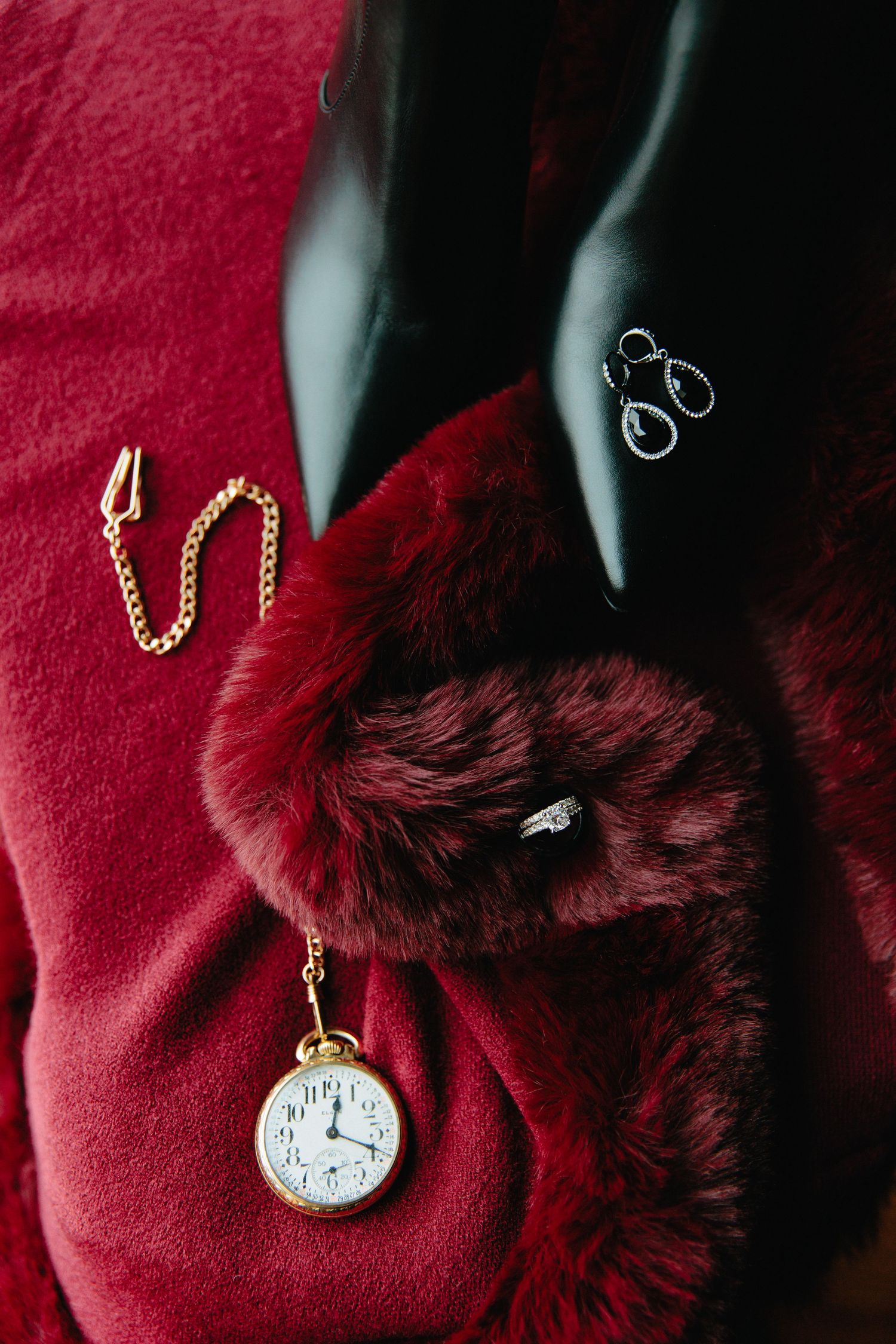 Vintage pocket watch with gold chain displayed against red velvet fabric.
