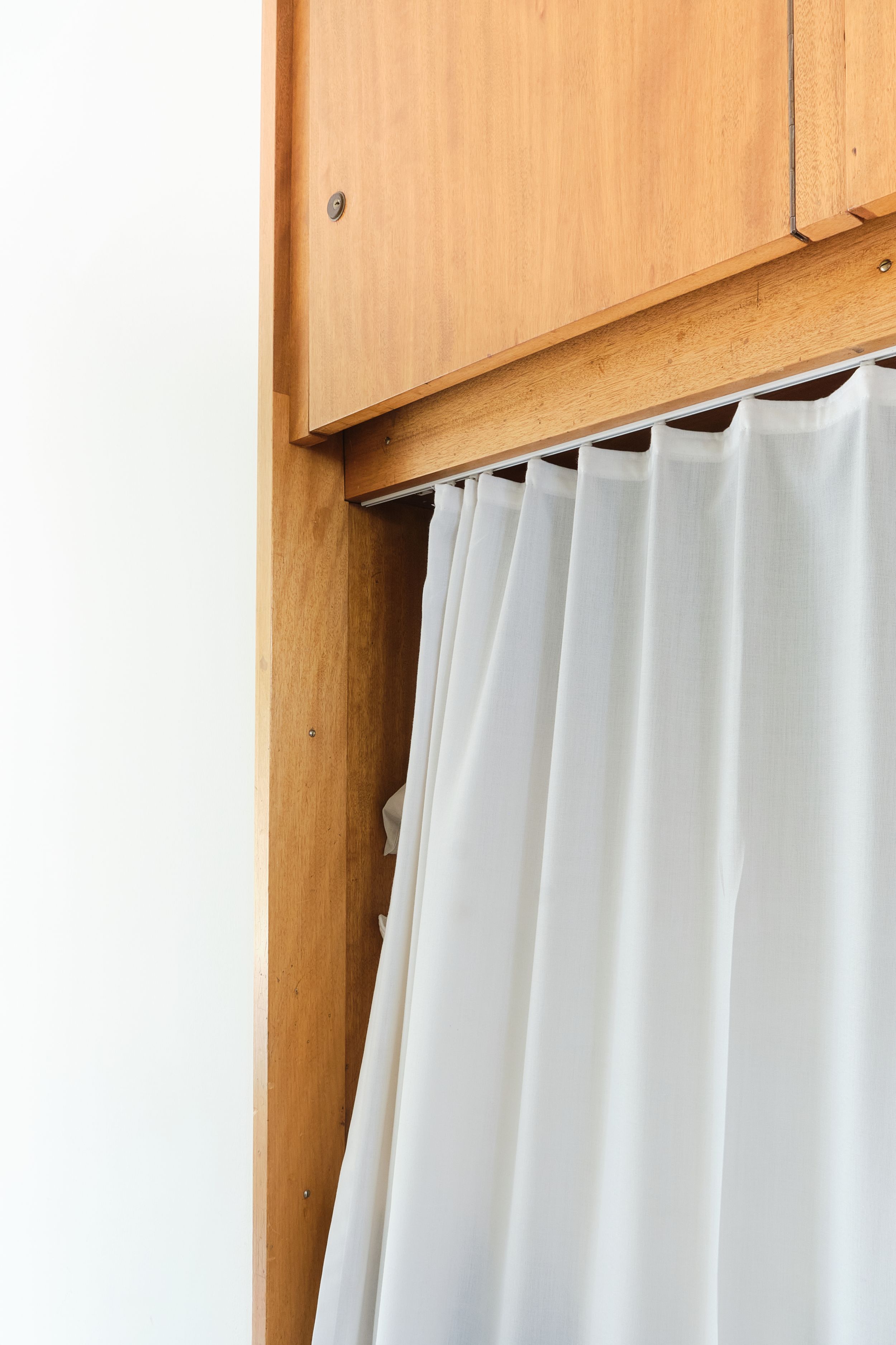 White curtains hanging against wooden walls create a clean, minimalist interior design aesthetic.