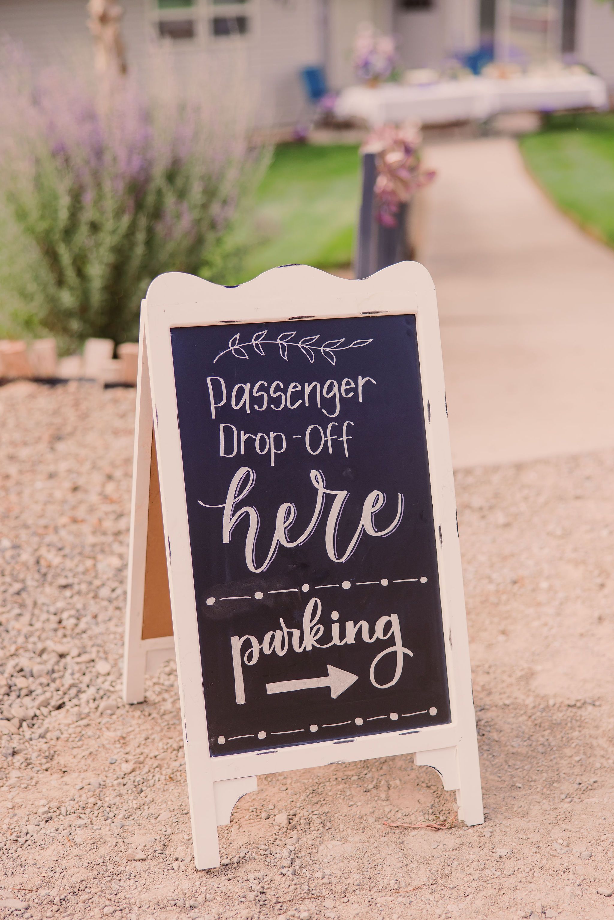 A white chalkboard sign on a stand displays 'Passenger Drop-off Here' with an arrow pointing to parking area.
