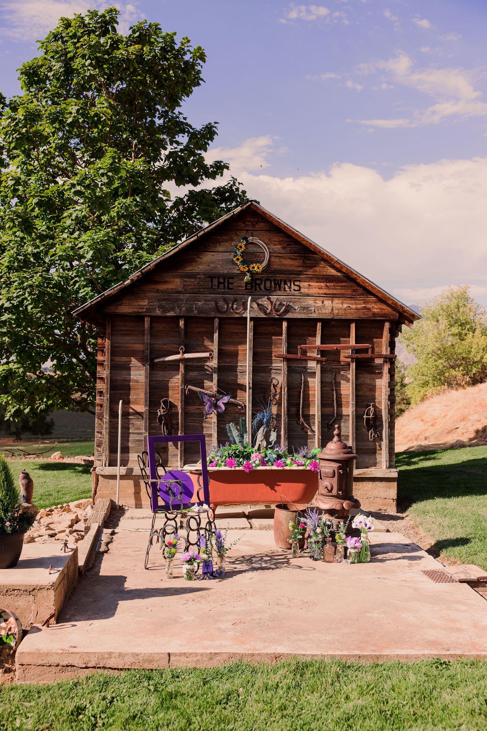 A rustic wooden cabin with a porch sits on a grassy hill against a blue sky with multiple viewing angles shown.