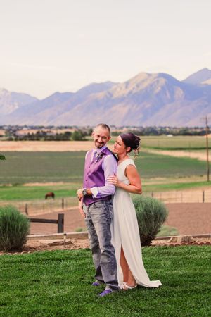 A couple embraces on a grassy lawn with scenic mountain views at sunset in Colorado.