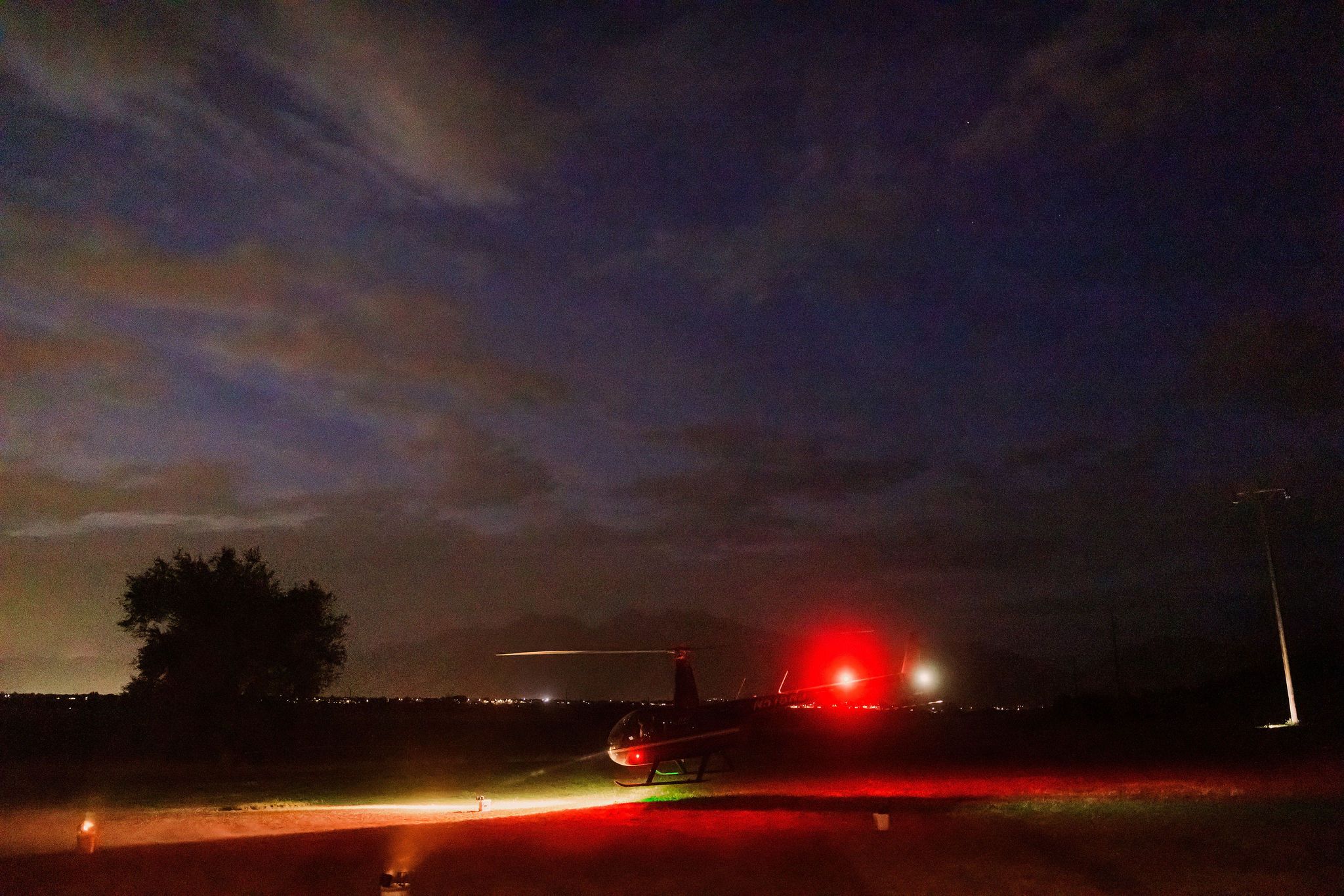 A series of long exposure photographs showing light trails across a dark rural landscape at dusk.