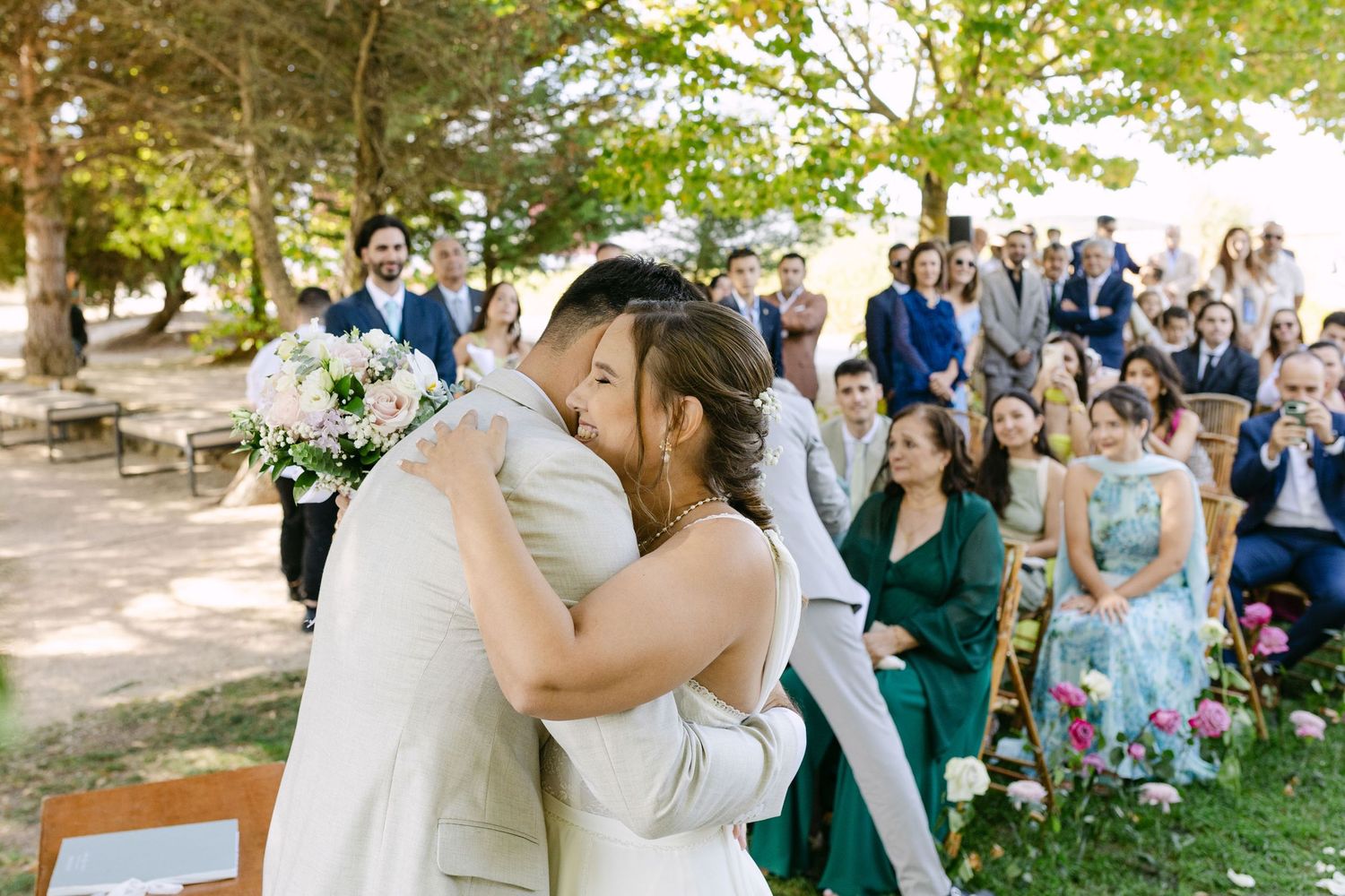 Bride and groom embracing during lakeside ceremony at Quinta da Bichinha in Alenquer