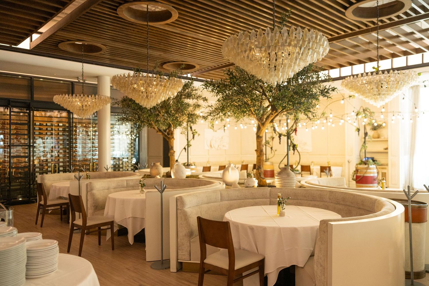 Elegant restaurant interior with crystal chandeliers, white tablecloths, and warm lighting creating an upscale dining atmosphere.