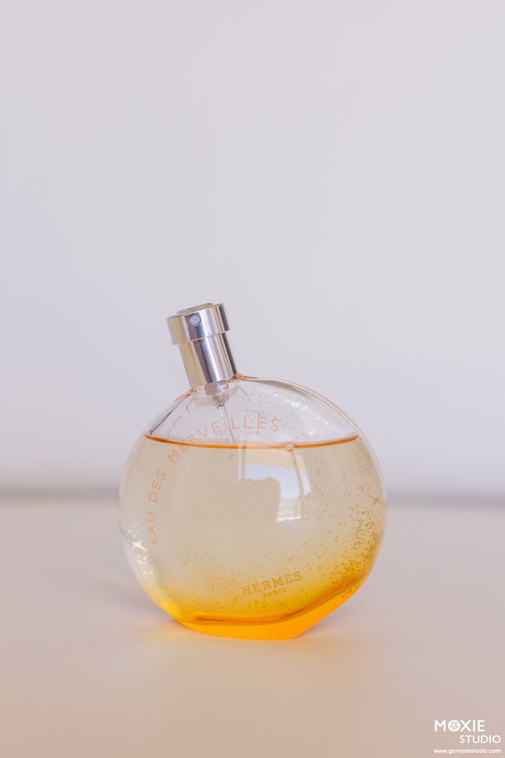 A minimalist perfume bottle photographed on white background with amber liquid inside.