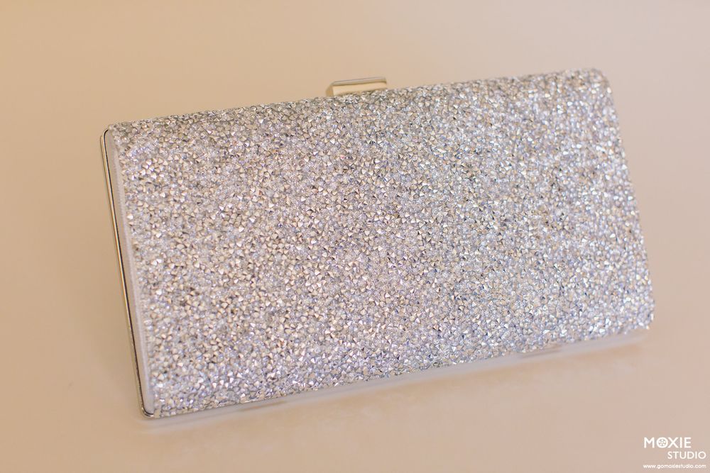 Close-up detail of a sparkly silver clutch purse or evening bag with glittery texture.