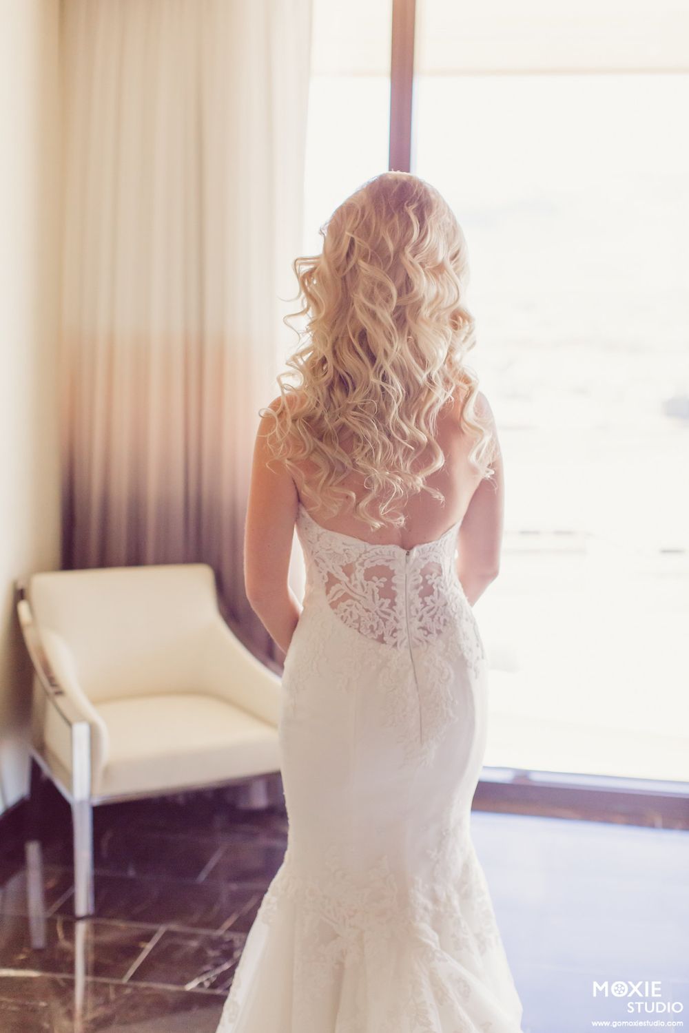 Back view of bride in lace mermaid wedding dress with elegant curled hairstyle.