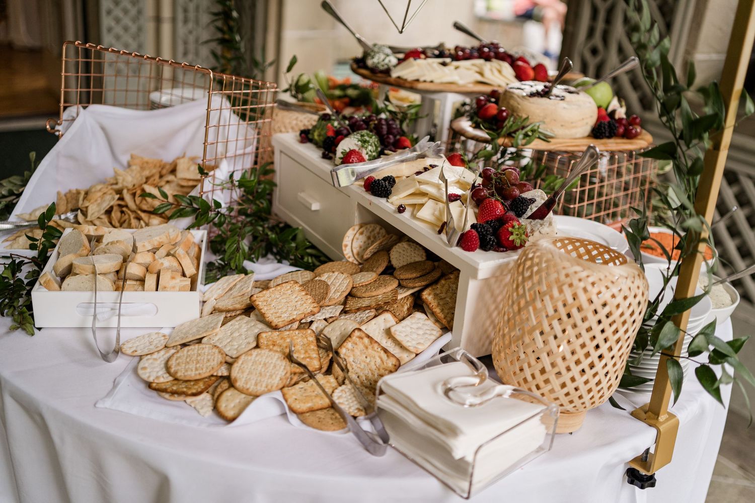 Rustic wedding dessert table display featuring cookies, pastries and greenery decorations arranged on wooden stands.