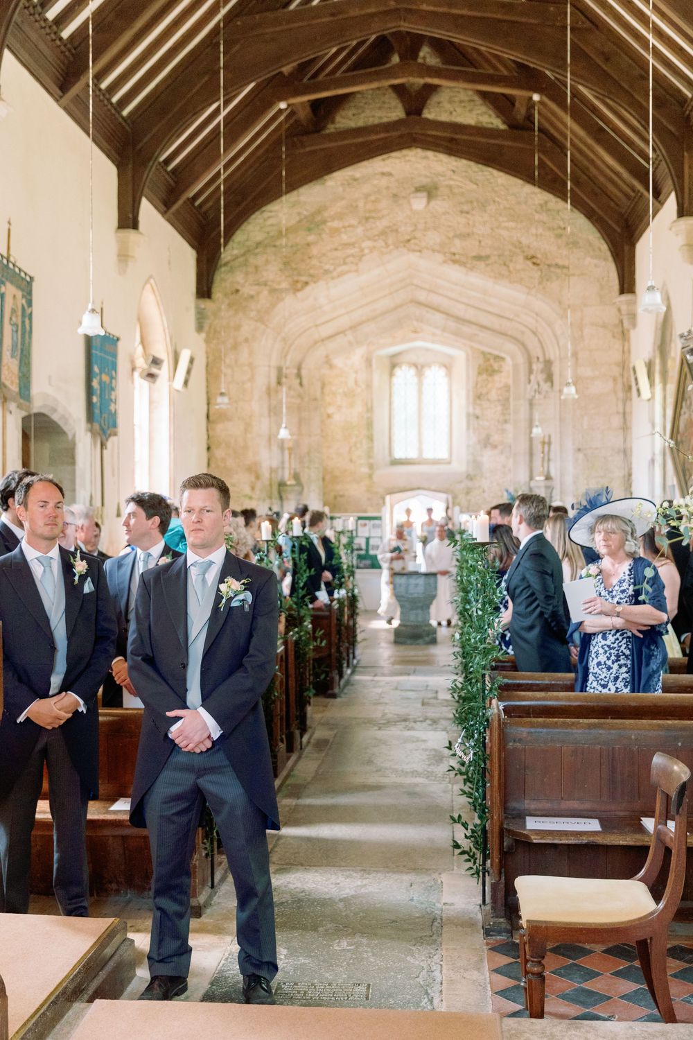 Traditional church interior with wooden beams and guests seated in pews for wedding ceremony.
