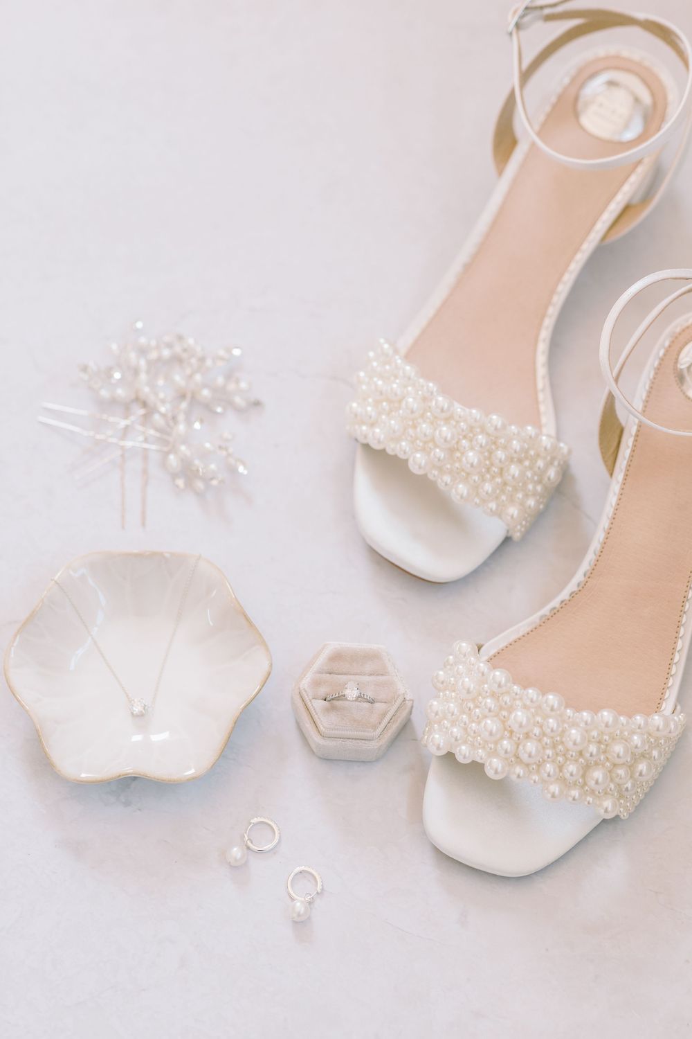 Elegant white bridal shoes with pearl embellishments displayed in a row against a light background.