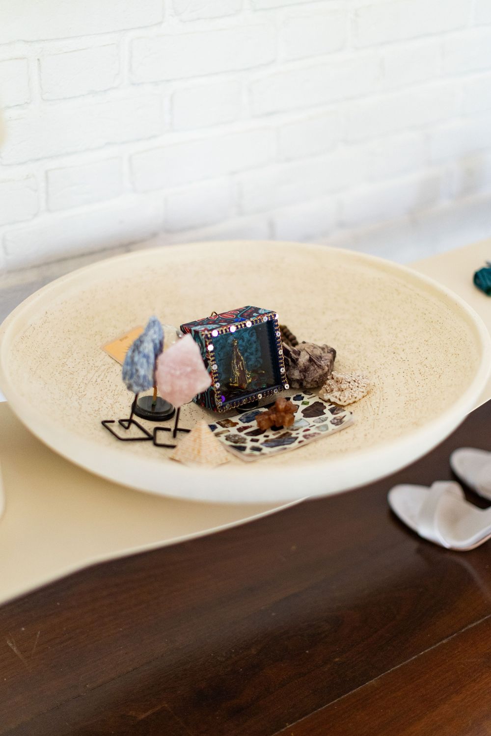 A series of white plates on a dark wooden table displaying small electronic components and decorative items.