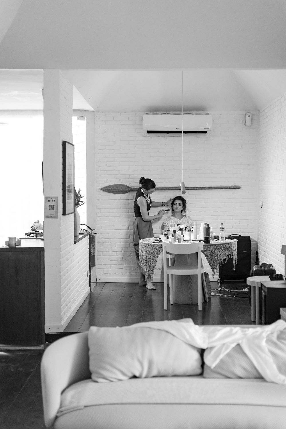 A black and white interior photo showing two people in a modern living space with a white couch in the foreground.