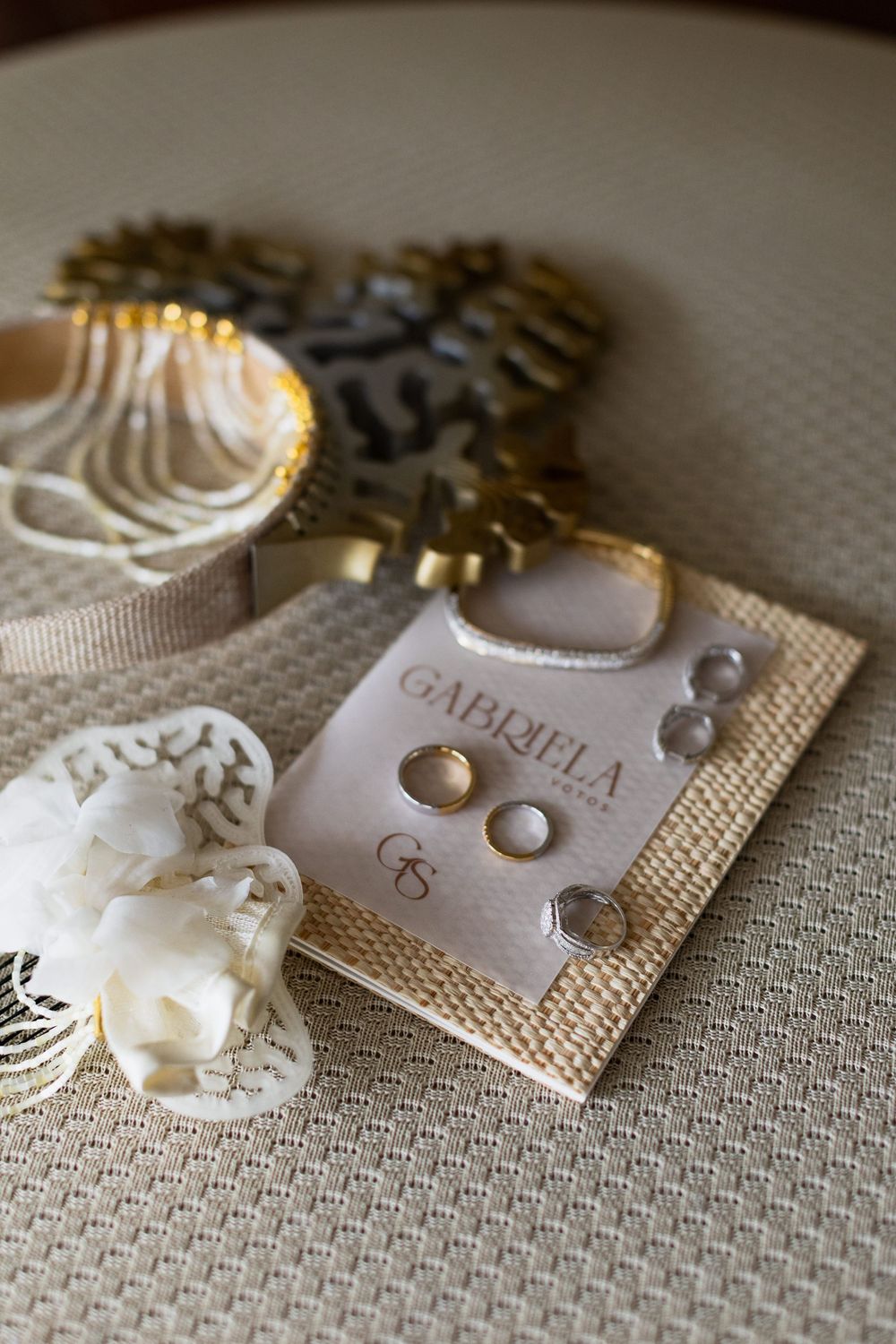 Pearl and gold earring studs displayed on textured beige linen fabric with branded jewelry cards.