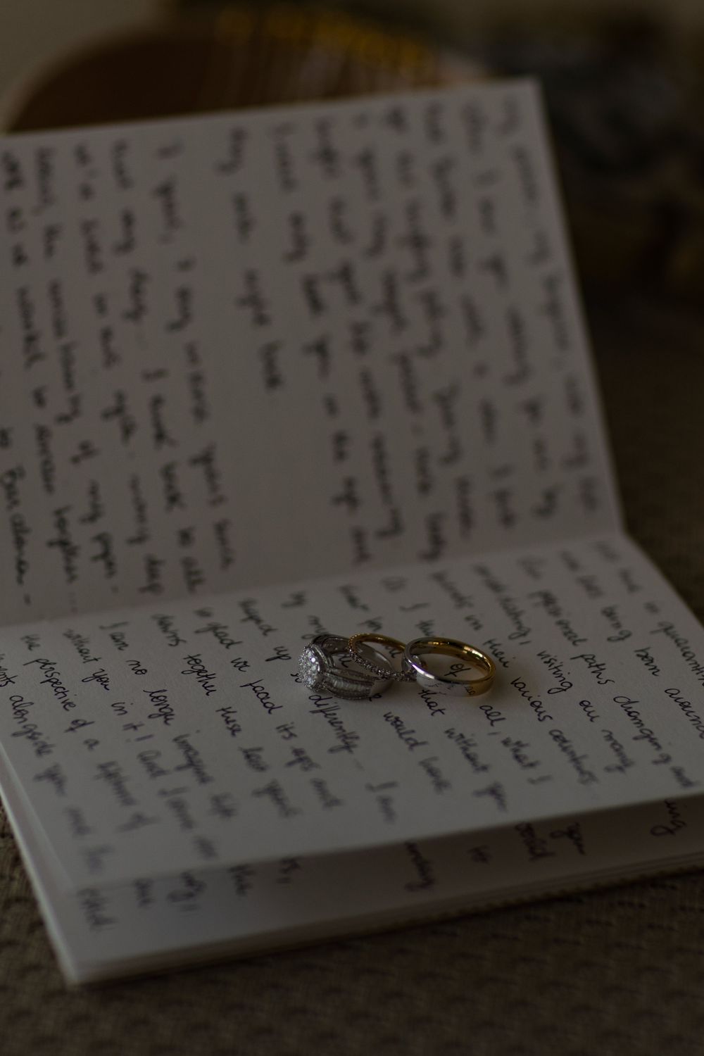 Two wedding rings rest on handwritten paper with cursive text creating an intimate and romantic scene.