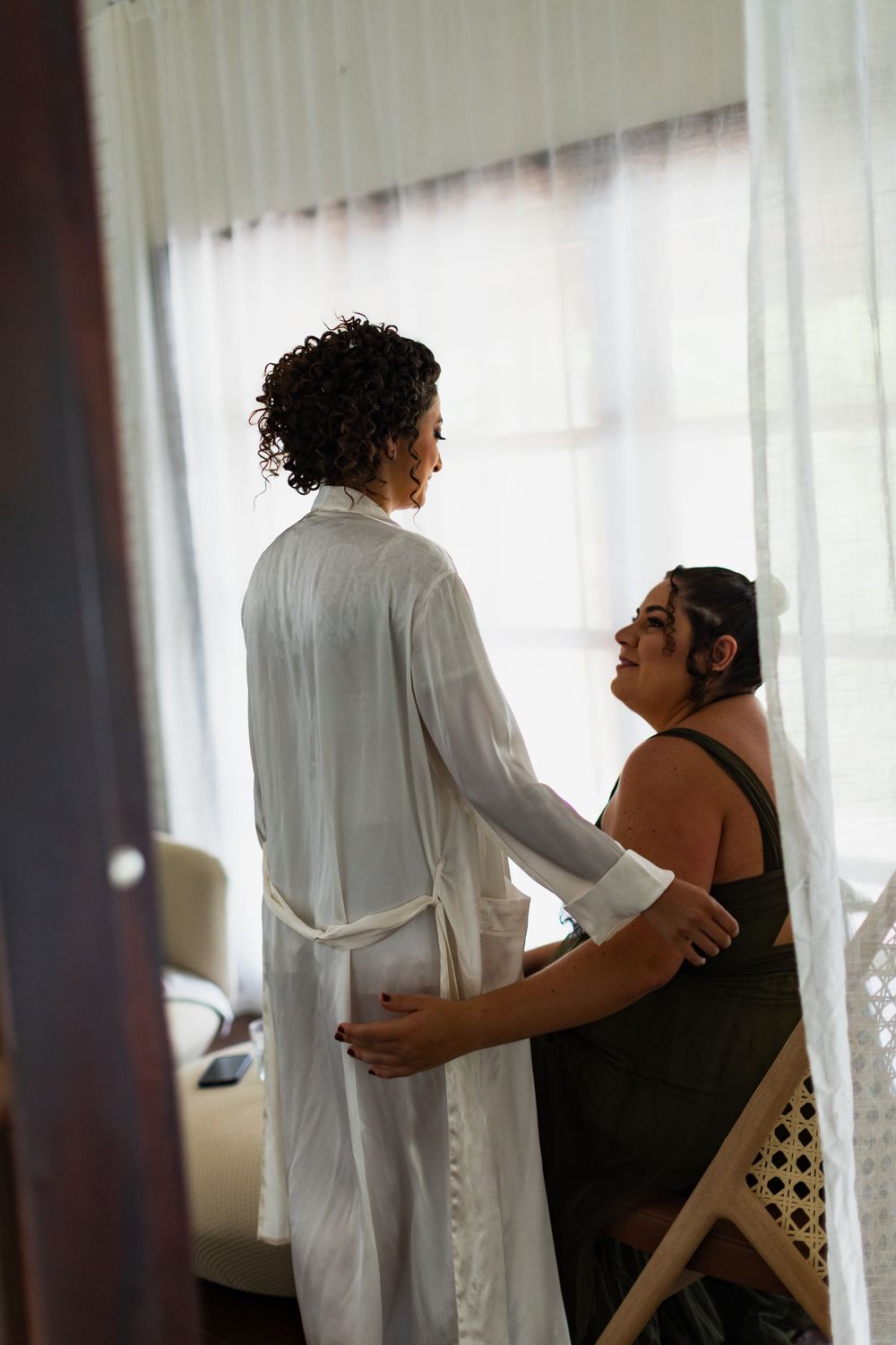 A series of tender moments showing a caregiver assisting someone in a black top by a window with sheer curtains.
