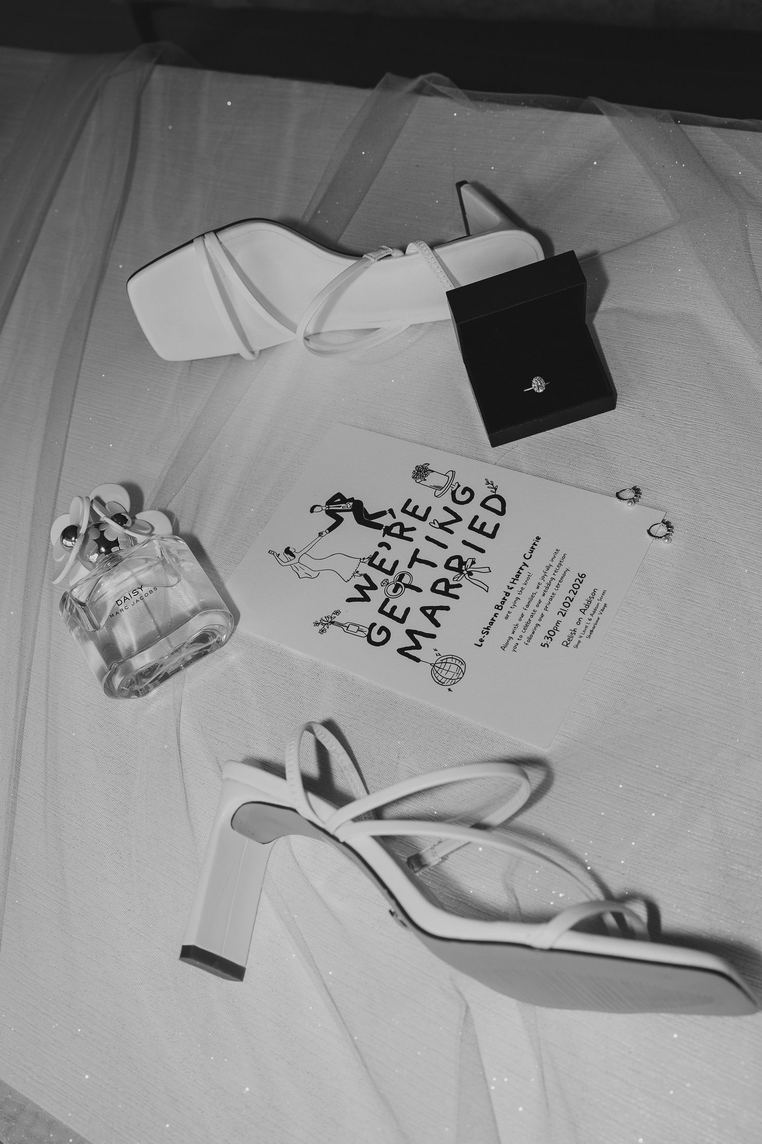 Black and white image showing white t-shirts with text and designs laid out on a surface.