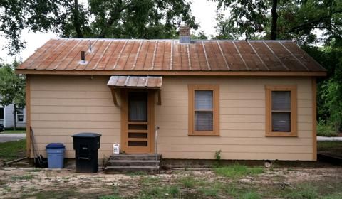 Panoramic exterior view of a rustic cabin with wooden siding and white trim.