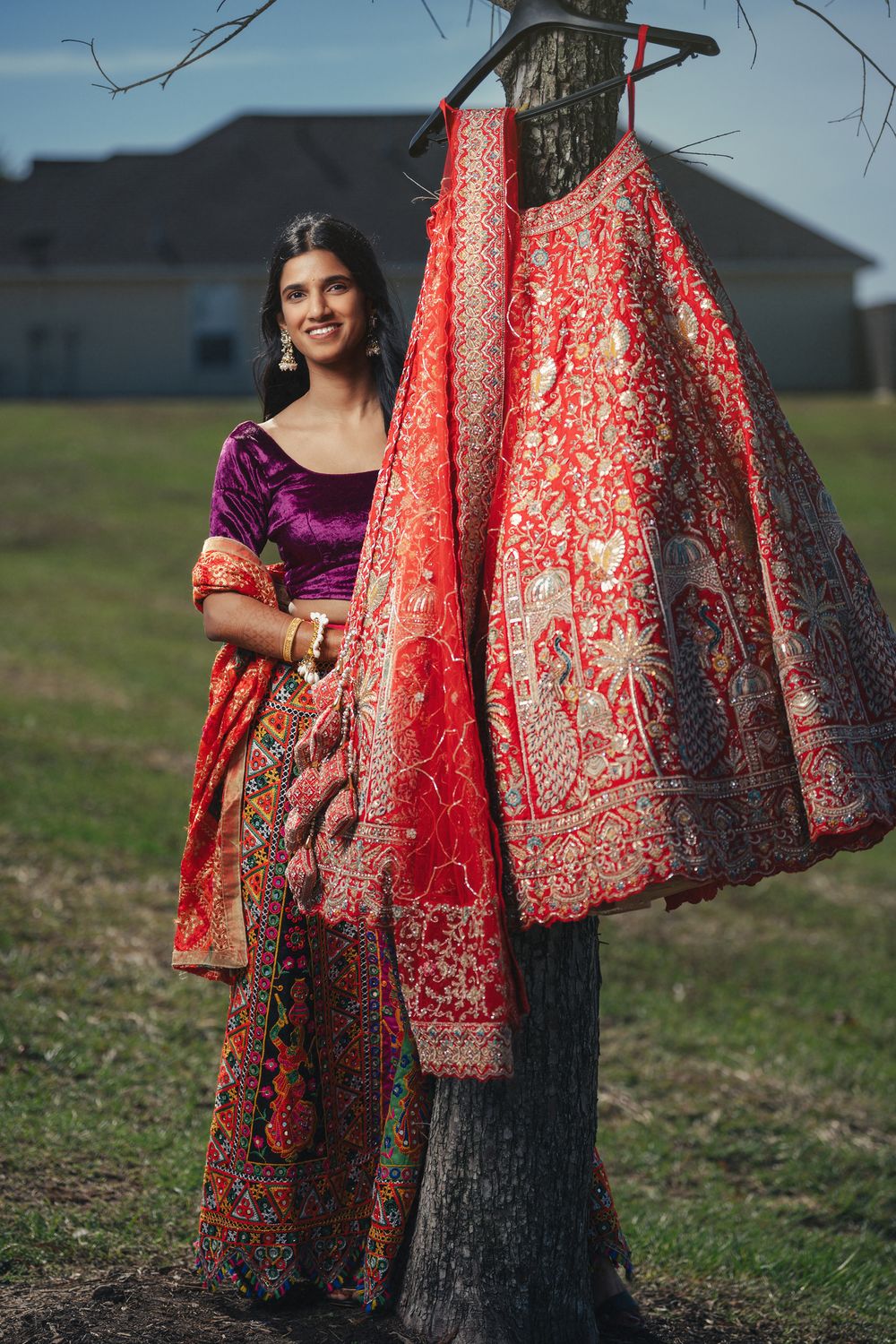 Traditional Indian bridal lehenga in vibrant red with intricate embroidery and gold details displayed outdoors.